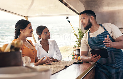 Buy stock photo Shot of two friends ordering food from a food truck