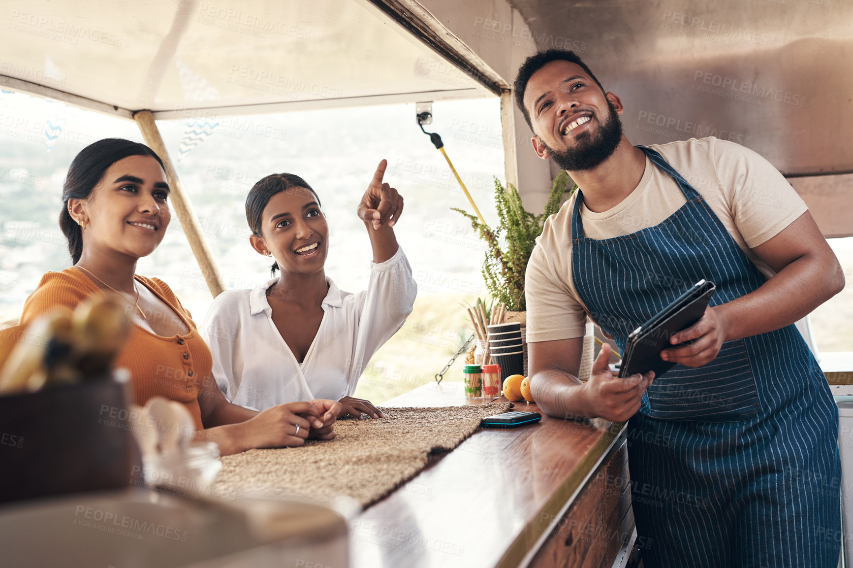 Buy stock photo Shot of two friends ordering food from a food truck