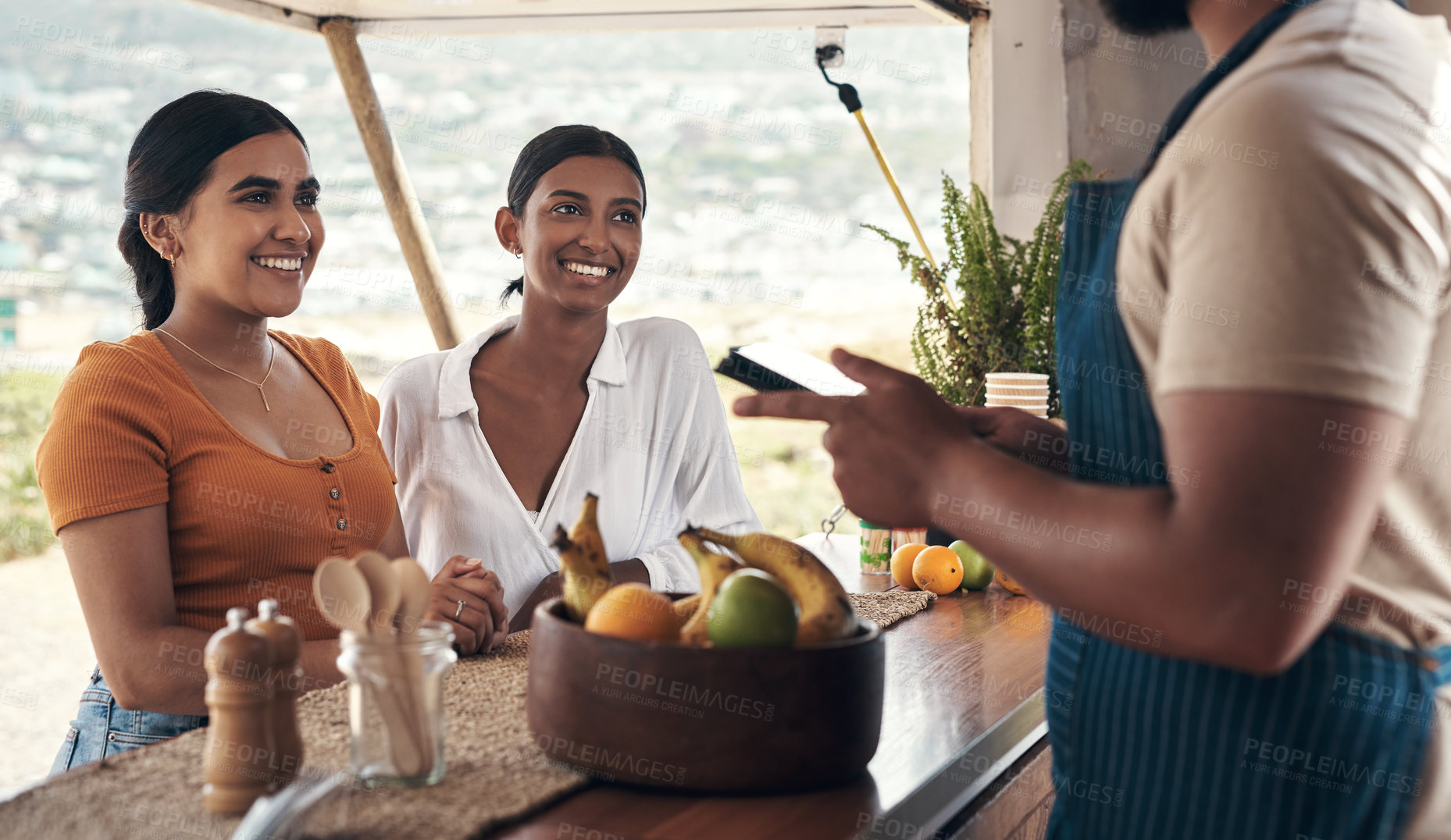 Buy stock photo Shot of two friends ordering food from a food truck