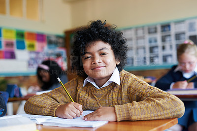 Buy stock photo Shot of a young boy sitting in his classroom at school during the day