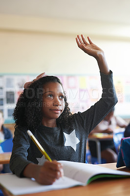 Buy stock photo Shot of a young girl sitting in her school classroom and raising her hand to answer a question