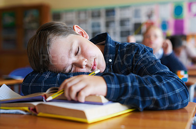 Buy stock photo Shot of a young boy asleep on his text books in his classroom at school during the day