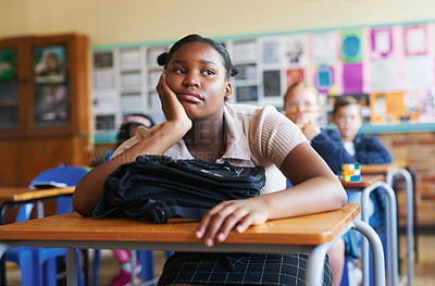 Buy stock photo Shot of a young girl sitting in her classroom at school and feeling bored