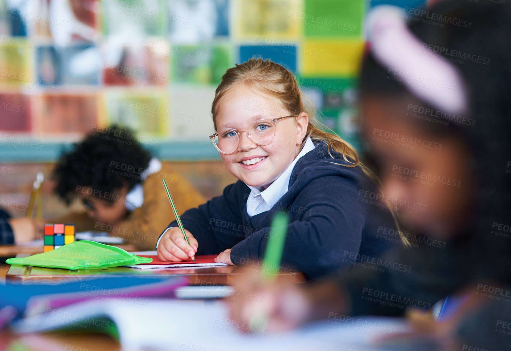 Buy stock photo Shot of a young girl sitting in her classroom at school and writing in her workbook