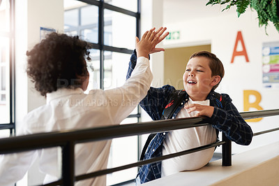 Buy stock photo Shot of two young boys standing together in the hallway at school and giving each other a high five