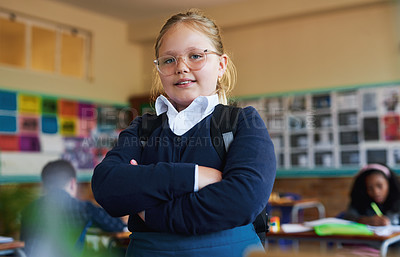 Buy stock photo Shot of a young girl standing in her classroom at school with her arms folded