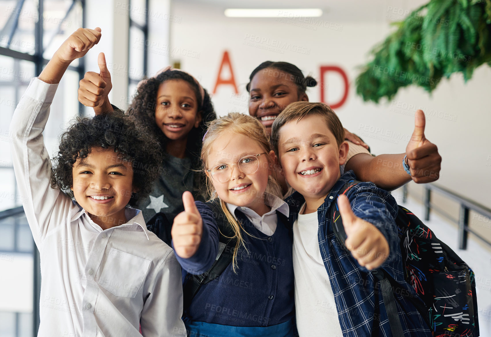 Buy stock photo Shot of a diverse group of children standing together in the hallway at school and giving a thumbs up gesture