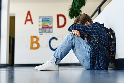 Buy stock photo Full length shot of an unrecognizable boy sitting alone in the hallway at school and feeling depressed