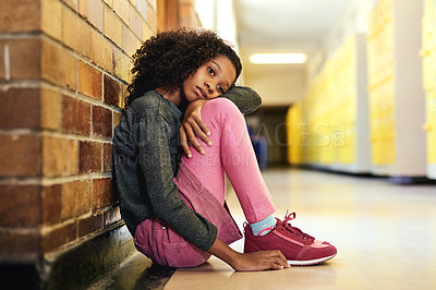 Buy stock photo Full length shot of a young girl sitting alone in the hallway at school and feeling depressed