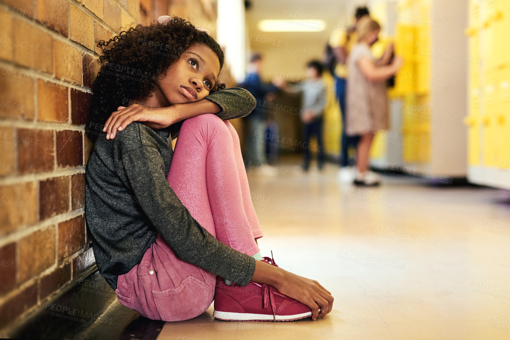 Buy stock photo Full length shot of a young girl sitting in the hallway at school and feeling depressed