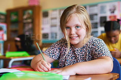 Buy stock photo Shot of a young girl sitting in her classroom at school and writing in her workbook
