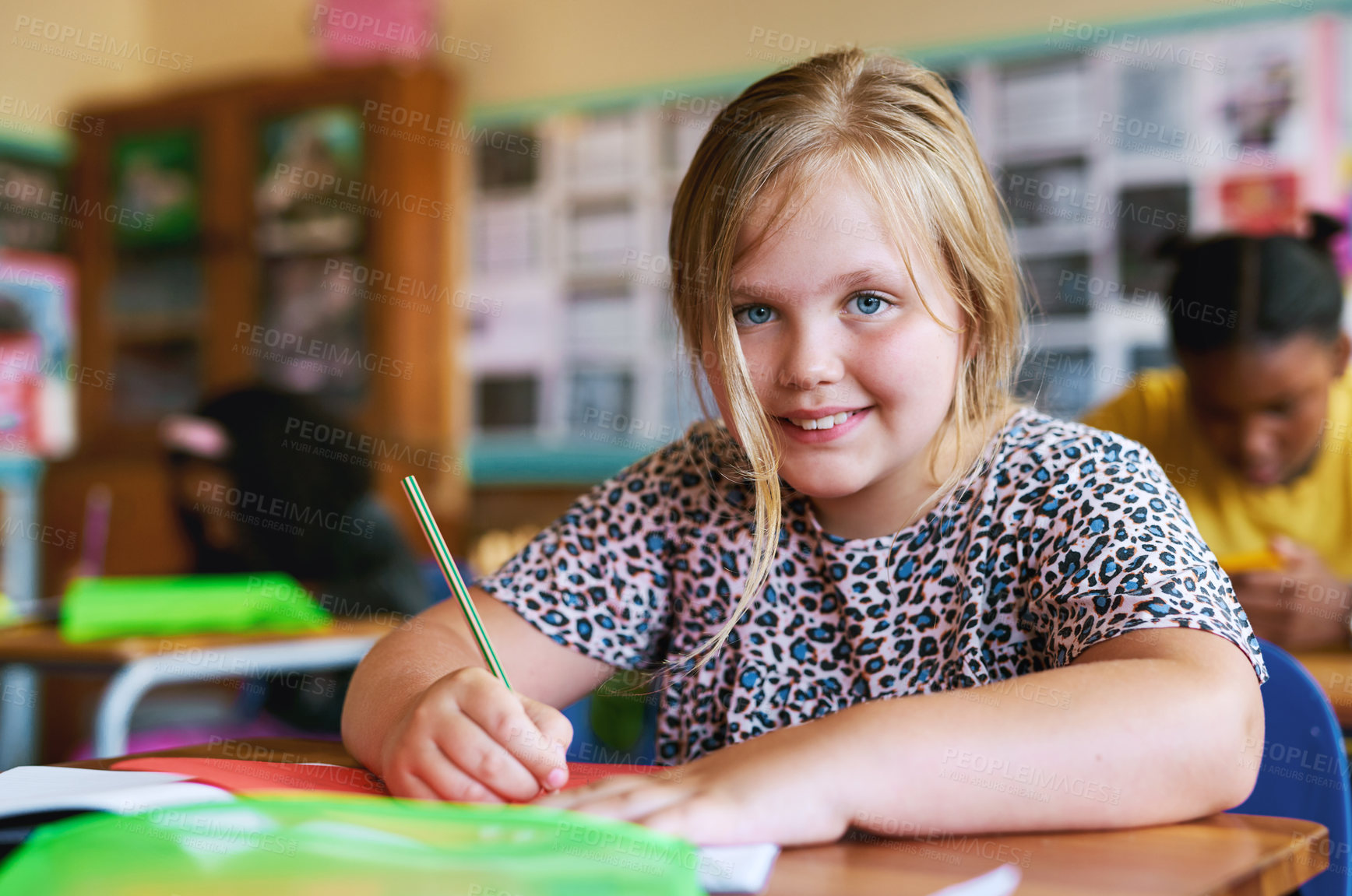 Buy stock photo Shot of a young girl sitting in her classroom at school and writing in her workbook