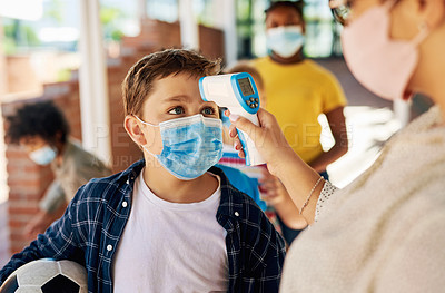 Buy stock photo Shot of a young boy wearing a mask and getting his temperature checked before going out to play during recess