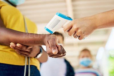 Buy stock photo Cropped shot of an unrecognizable woman standing and using a thermometer to check her students' temperatures at school