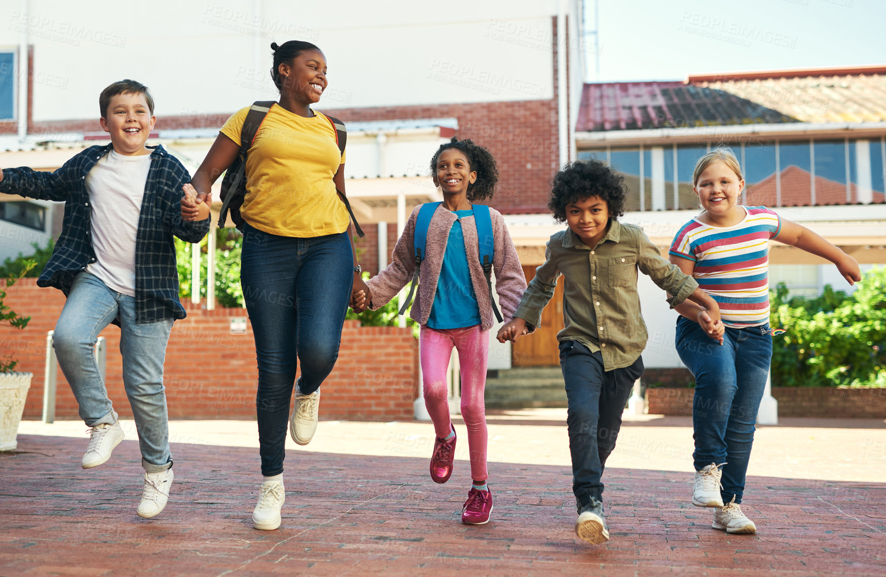 Buy stock photo Full length shot of a diverse group of children skipping outside during recess at school