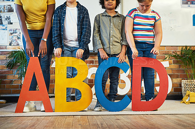 Buy stock photo Cropped shot of a diverse group of children standing and holding the alphabet letters in their classroom at school