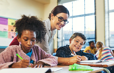 Buy stock photo Shot of an attractive young teacher helping a student in her classroom during a lesson