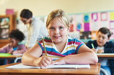 Buy stock photo Shot of a young girl sitting in her classroom at school and writing in her workbook