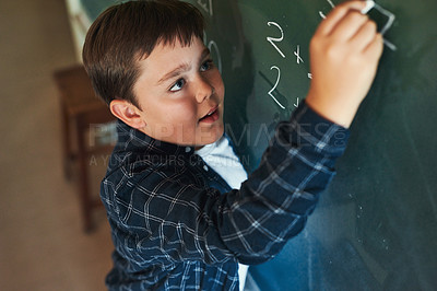 Buy stock photo Shot of a young boy standing alone and writing on the blackboard during a lesson in his classroom at school