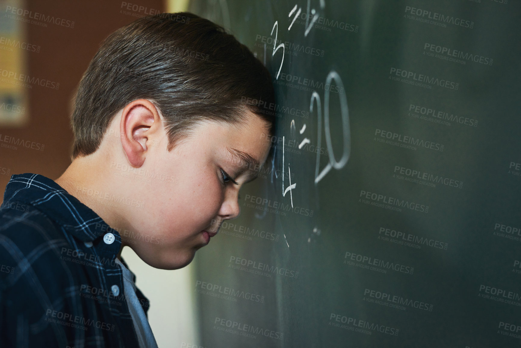 Buy stock photo Shot of a young boy standing and feeling depressed while trying to answer a question on the blackboard at school