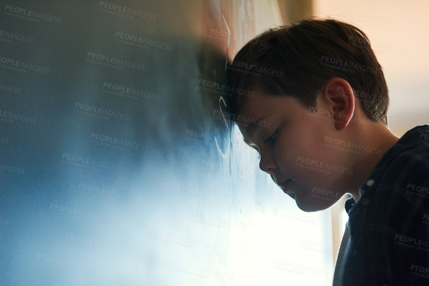 Buy stock photo Shot of a young boy standing and feeling depressed while trying to answer a question on the blackboard at school