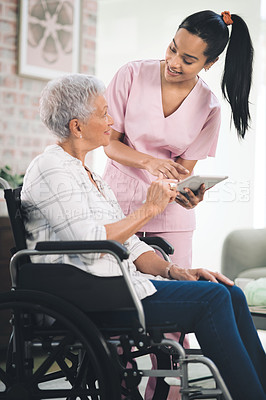 Buy stock photo Shot of a young nurse sharing information from her digital tablet with an older woman in a wheelchair