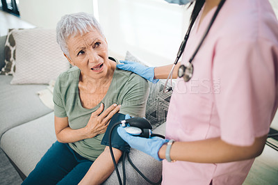 Buy stock photo Shot of a concerned older woman having her blood pressure read at home