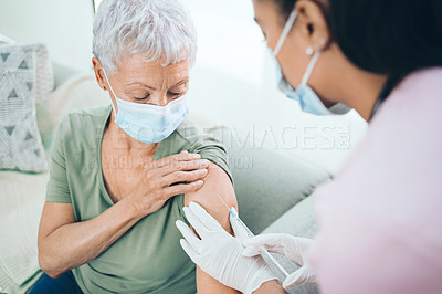 Buy stock photo Shot of a doctor giving a masked older woman an injection at home