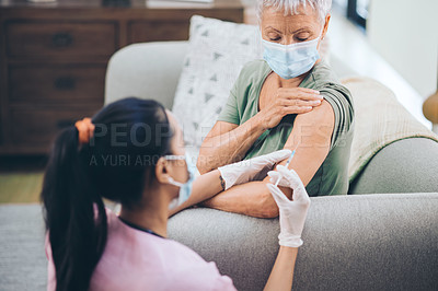 Buy stock photo Shot of a doctor giving a masked older woman an injection at home