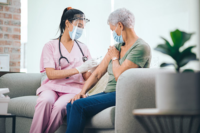 Buy stock photo Shot of a doctor giving a masked older woman an injection at home