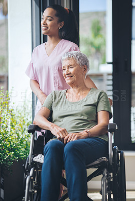 Buy stock photo Shot of a young nurse walking beside and pushing an older woman in a wheelchair