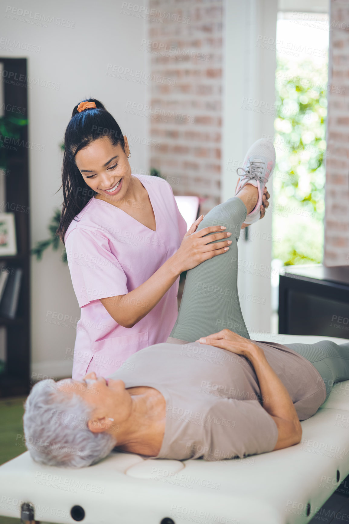 Buy stock photo Shot of an older woman doing light exercises during a session with a physiotherapist inside