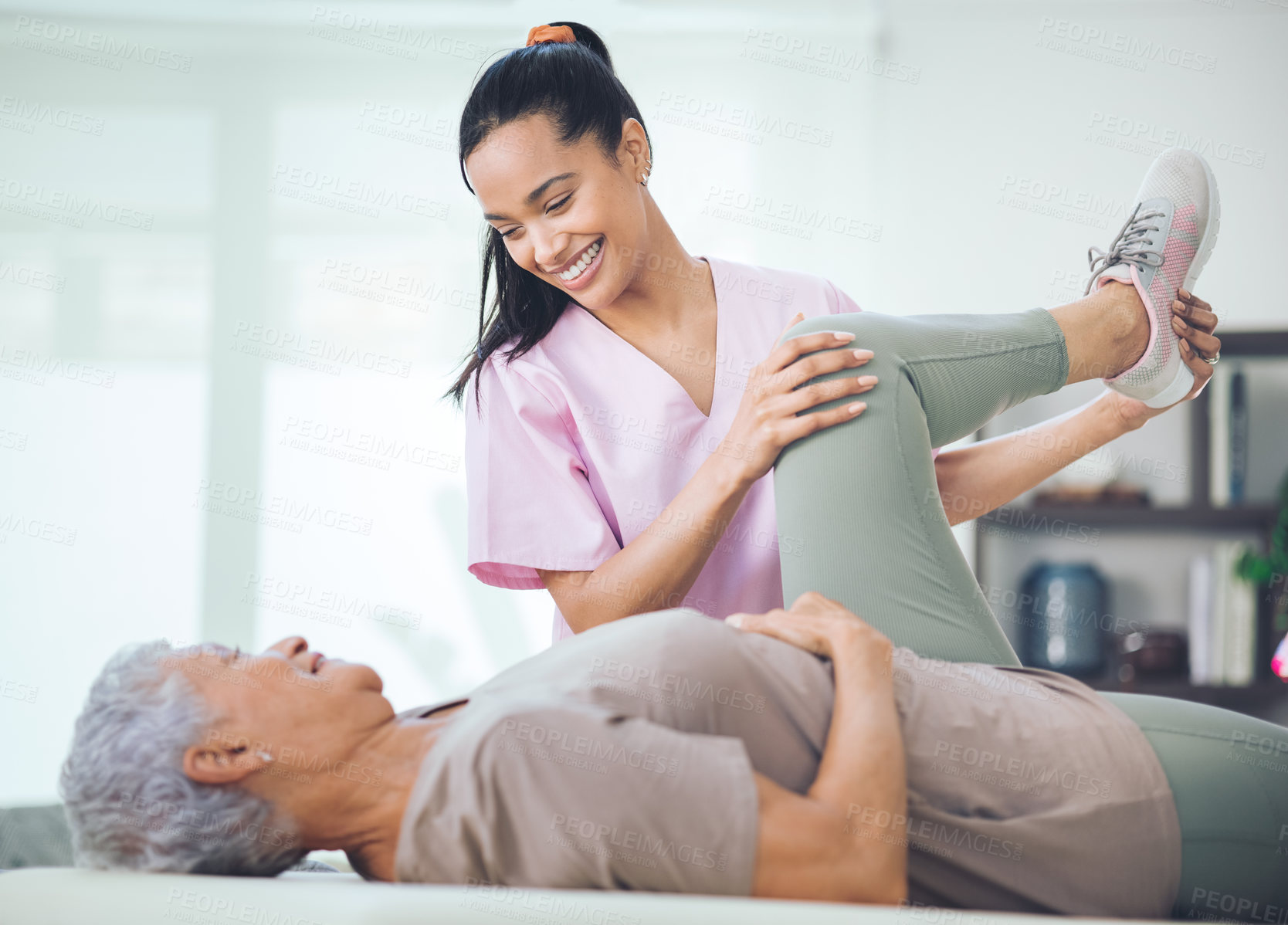 Buy stock photo Shot of an older woman doing light exercises during a session with a physiotherapist inside