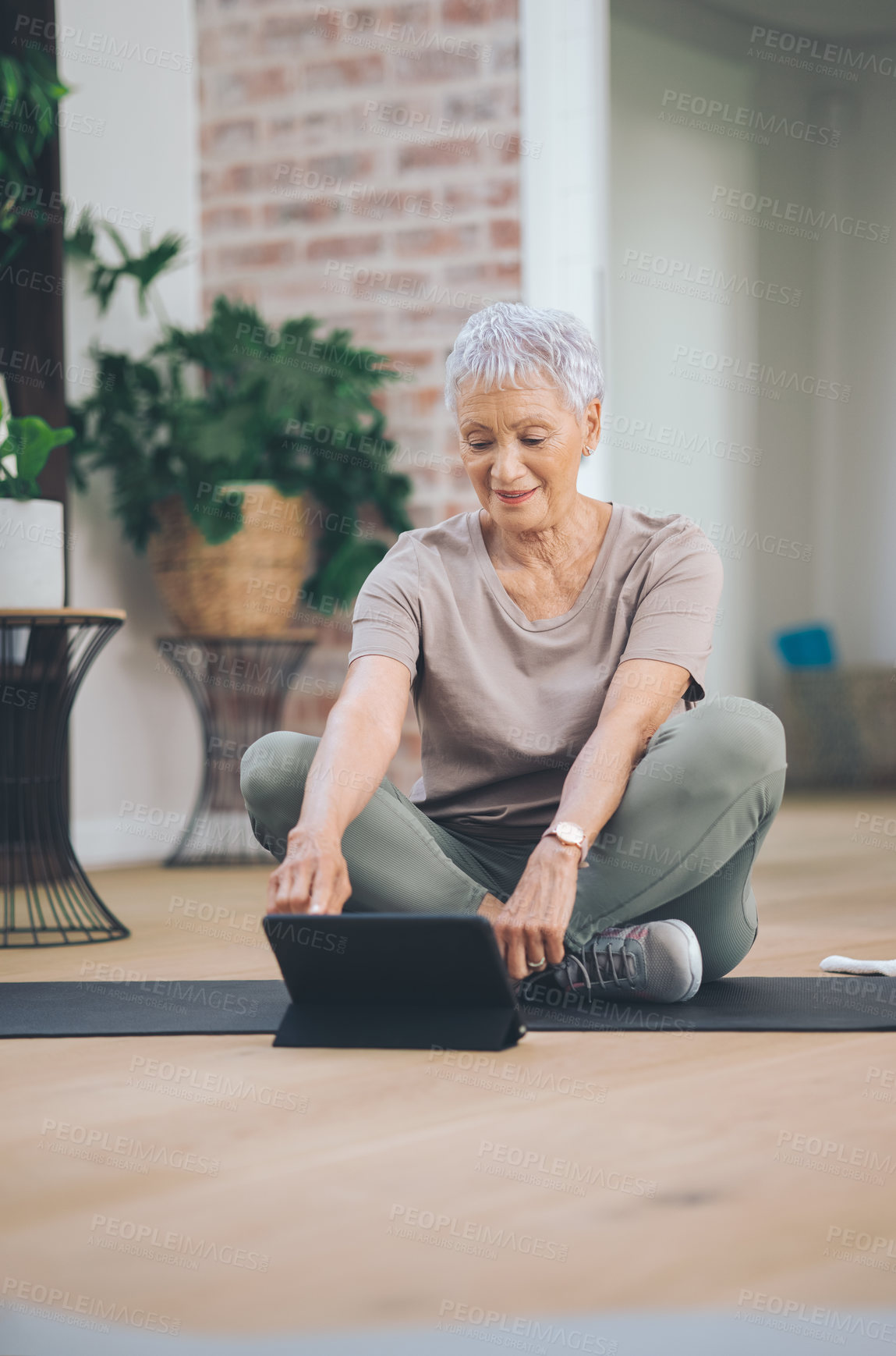 Buy stock photo Shot of an older woman using a digital tablet while sitting in the floor at home