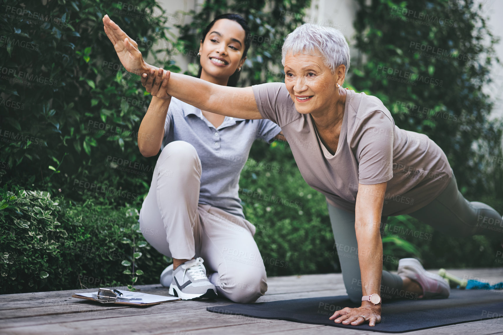 Buy stock photo Shot of an older woman doing light floor exercises during a session with a physiotherapist outside