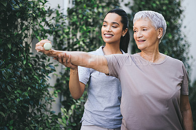 Buy stock photo Shot of an older woman lifting a dumbbell during a session with a physiotherapist