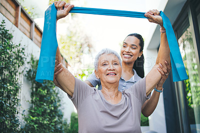 Buy stock photo Shot of an older woman using a resistance band during a session with a physiotherapist