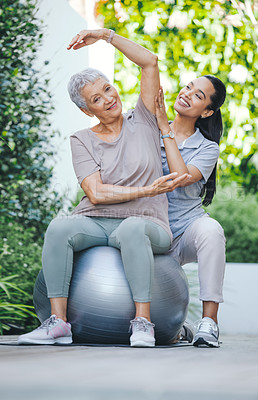 Buy stock photo Shot of an older woman using an exercise ball during a session with a physiotherapist outside