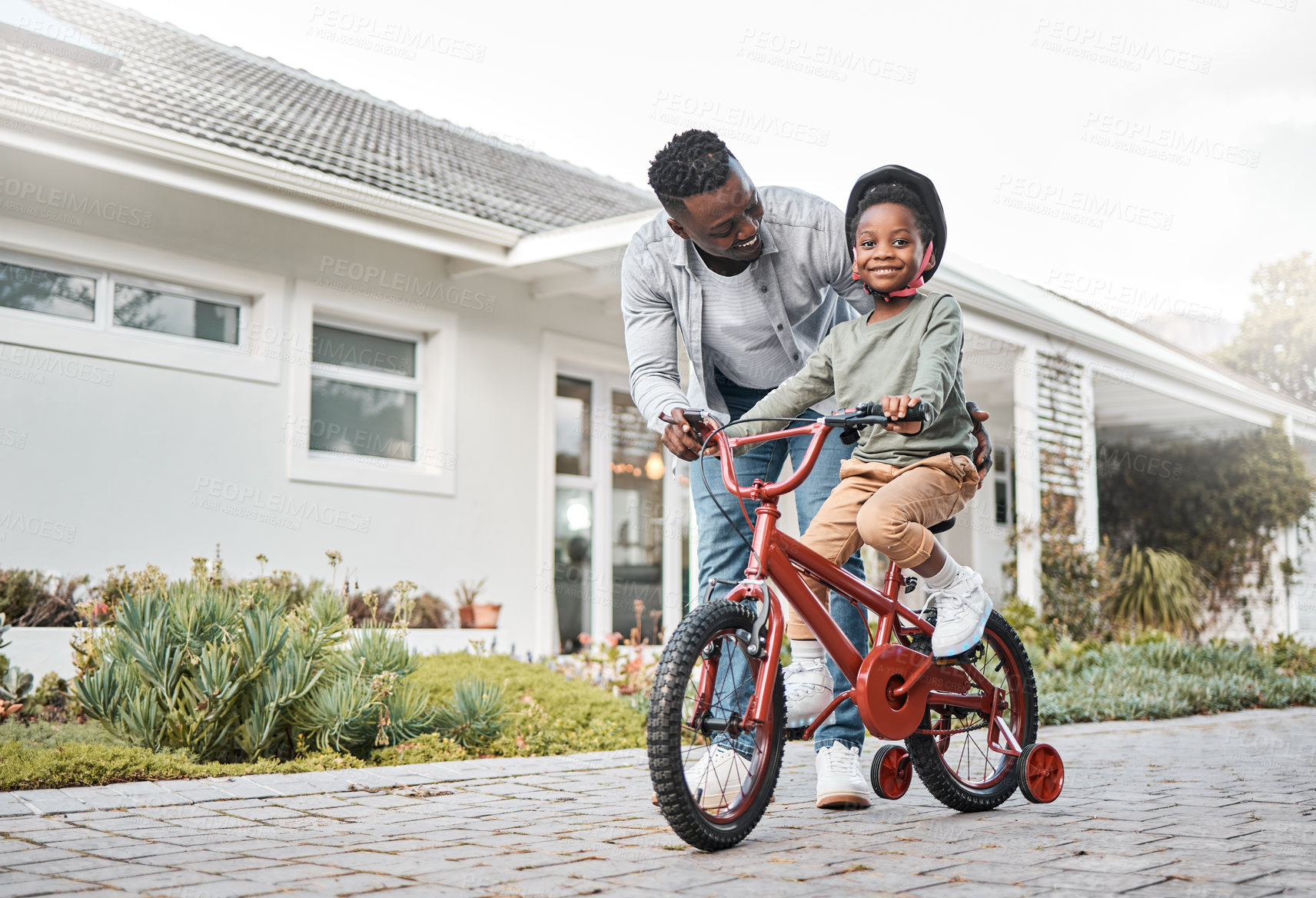 Buy stock photo Bicycle, learning and portrait of boy with dad on home driveway for bonding or child development. Black family, cycling and smile of son with single parent man outdoor together for balance or growth