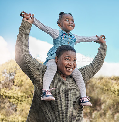 Buy stock photo Shot of a mother carrying her daughter on her shoulders outdoors