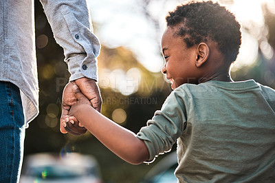 Buy stock photo Rearview shot of a little boy holding his father's hand while walking together outdoors