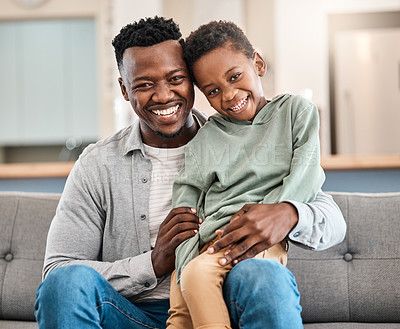 Buy stock photo Shot of an adorable little boy spending quality time with his father on the sofa at home