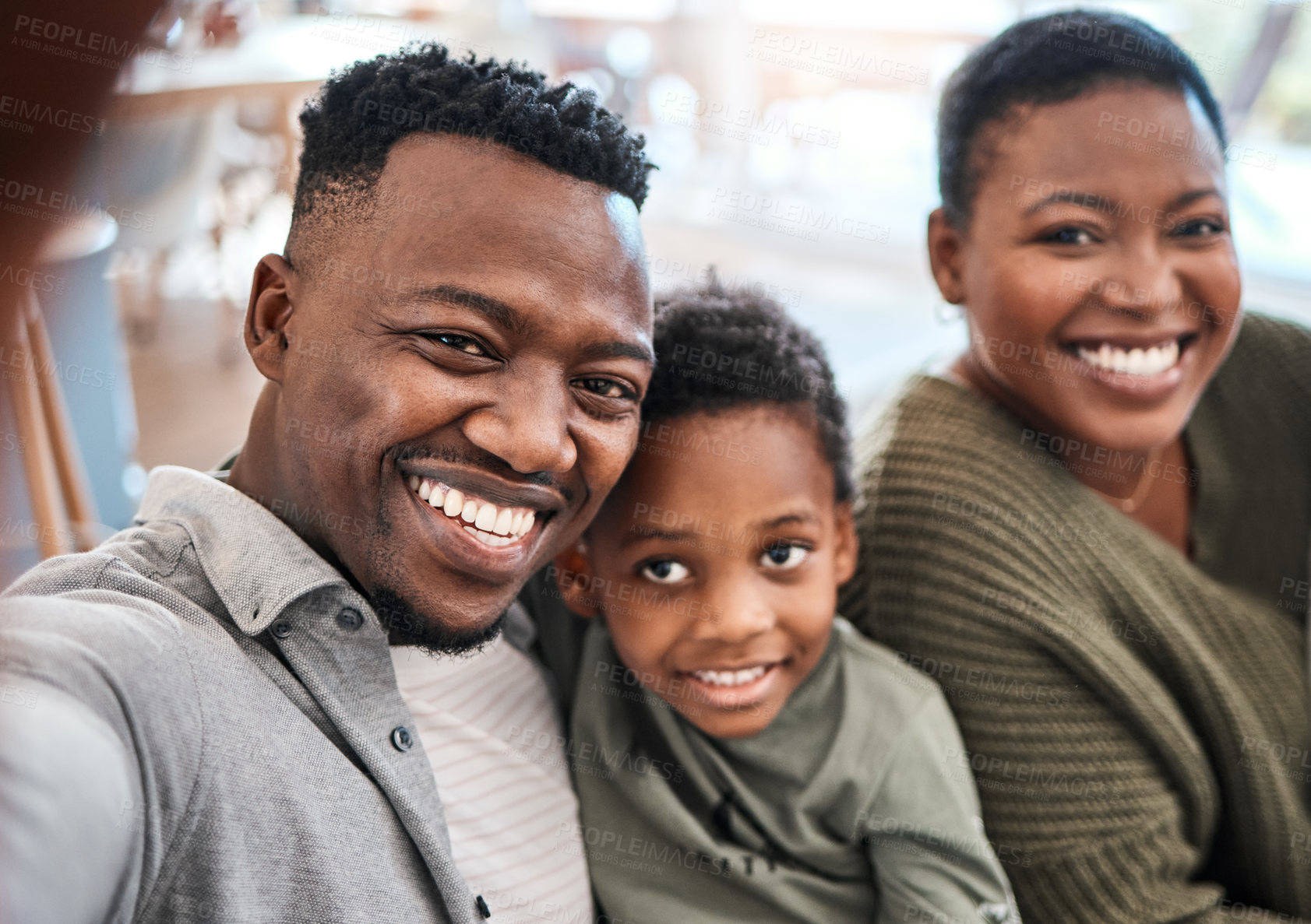 Buy stock photo Shot of a happy young family taking selfies on the sofa at home