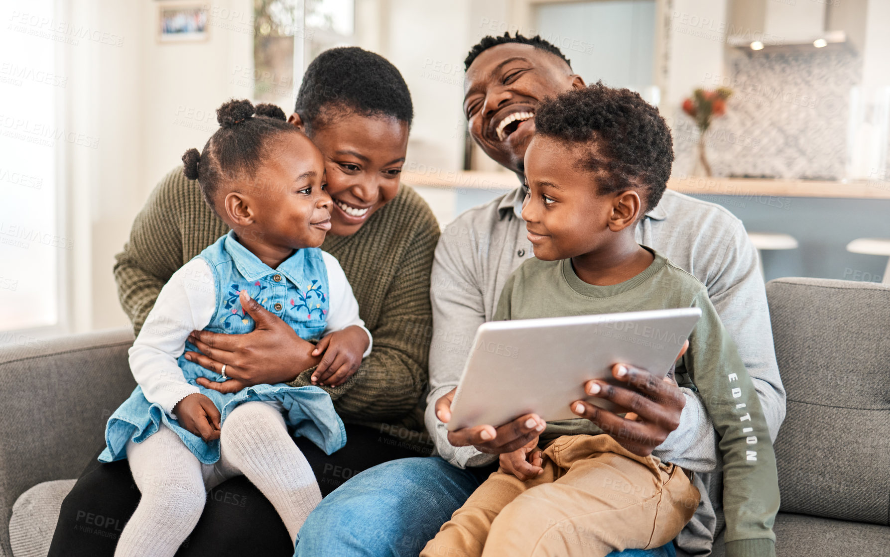 Buy stock photo Shot of a happy young family using a digital tablet on the sofa at home