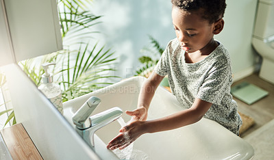 Buy stock photo High angle shot of a boy washing his hands at a tap in a bathroom at home