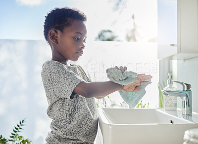 Buy stock photo Shot of a little boy drying his hands with a towel in a bathroom at home