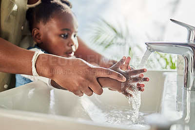 Buy stock photo Closeup shot of a mother helping her daughter wash her hands at a tap in a bathroom at home