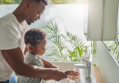 Buy stock photo Shot of a father helping his son wash his hands at a tap in a bathroom at home