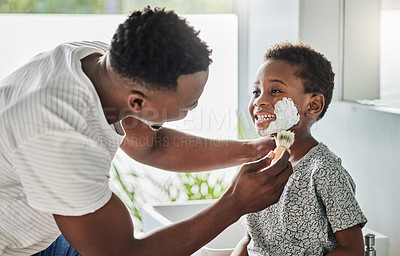 Buy stock photo Shot of a father applying shaving cream to his son's face in a bathroom at home