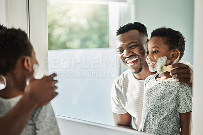 Buy stock photo Shot of a father applying shaving cream to his son's face in a bathroom at home